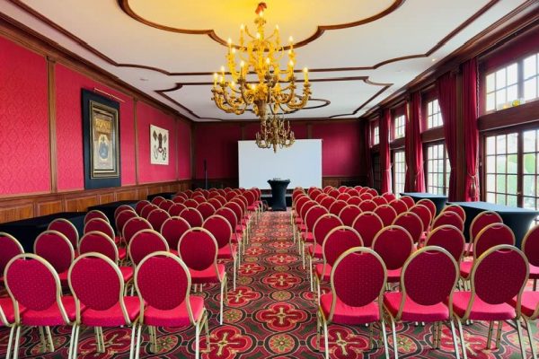 "Salle de conférence élégante : ambiance luxueuse avec sièges rouges et lustre doré"