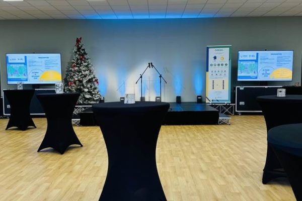 "Salle polyvalente prête pour un séminaire : espace moderne avec tables hautes et écrans de présentation"