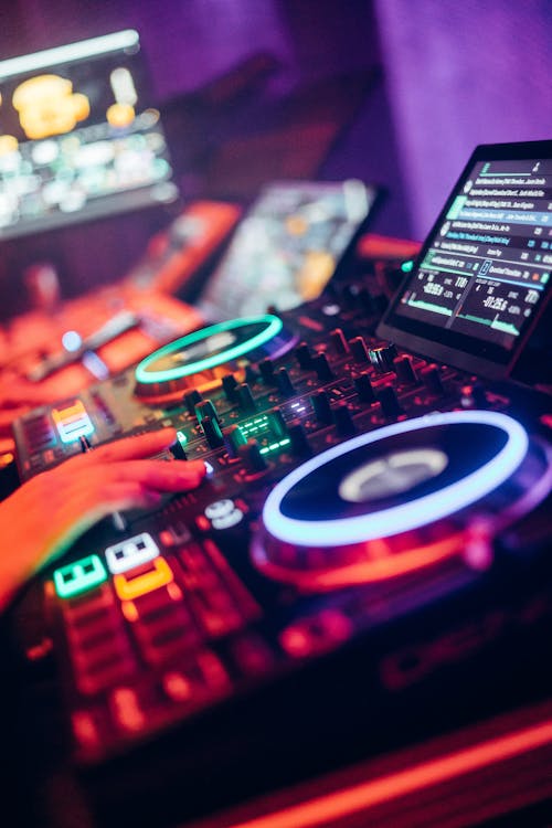 Contrôleur DJ lumineux avec platines et écran affichant des menus, ambiance nuit colorée et matériel audiovisuel pro. Contrôleur DJ lumineux avec platines et écran affichant des menus, ambiance nuit colorée et matériel audiovisuel pro.