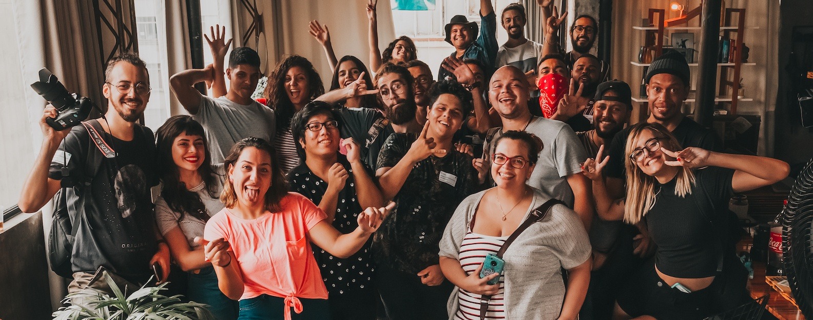Groupe enthousiaste de professionnels et stagiaires posant ensemble dans un espace intérieur, certains avec matériel photo, tous souriants et faisant des gestes festifs. Groupe enthousiaste de professionnels et stagiaires posant ensemble dans un espace intérieur, certains avec matériel photo, tous souriants et faisant des gestes festifs.