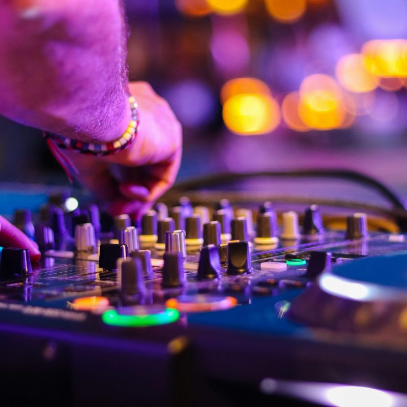 Gros plan sur les mains d'un DJ en pleine action, manipulant une table de mixage et des platines lors d'un événement.