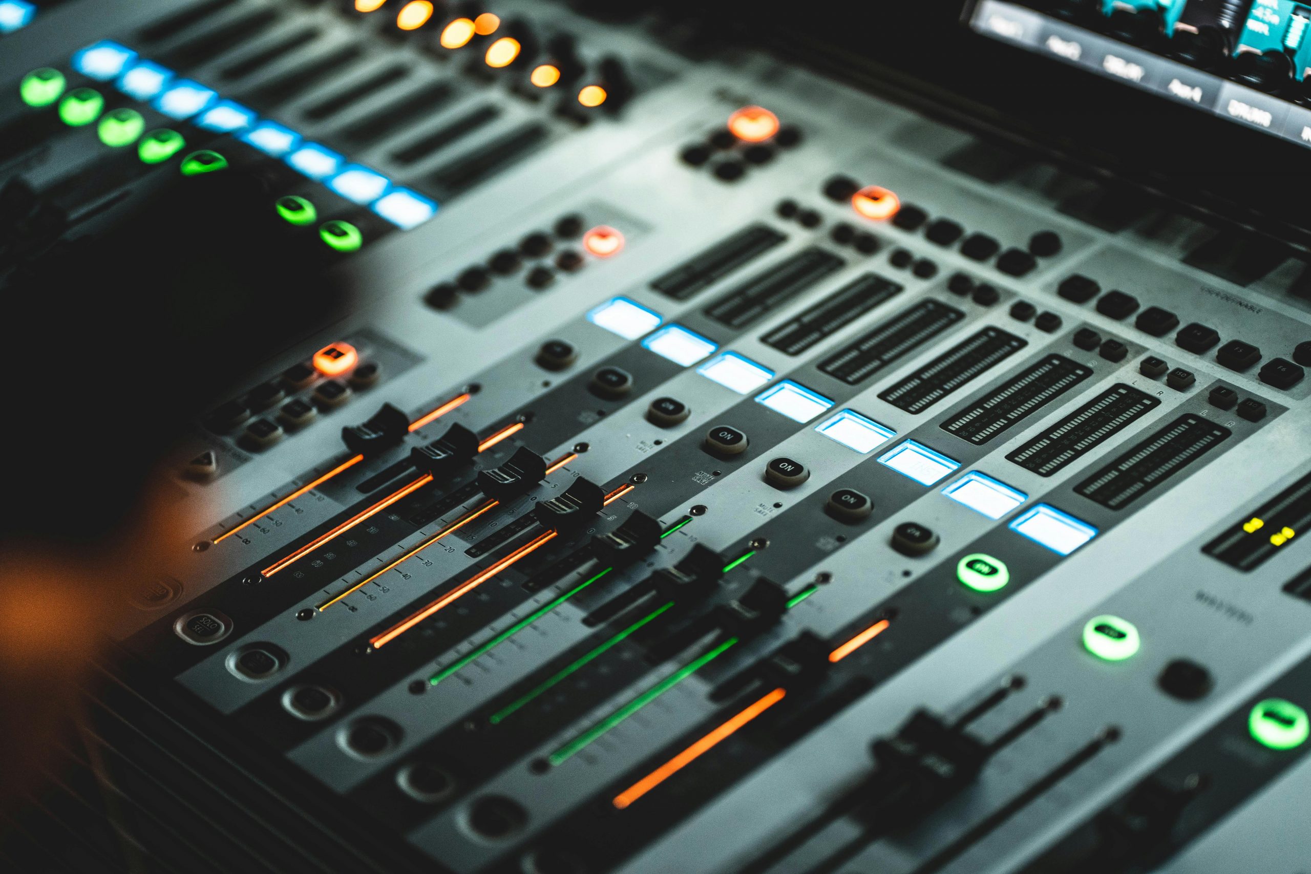 Table de mixage audio professionnelle avec faders colorés et voyants lumineux, utilisée en événements. Table de mixage audio professionnelle avec faders colorés et voyants lumineux, utilisée en événements.
