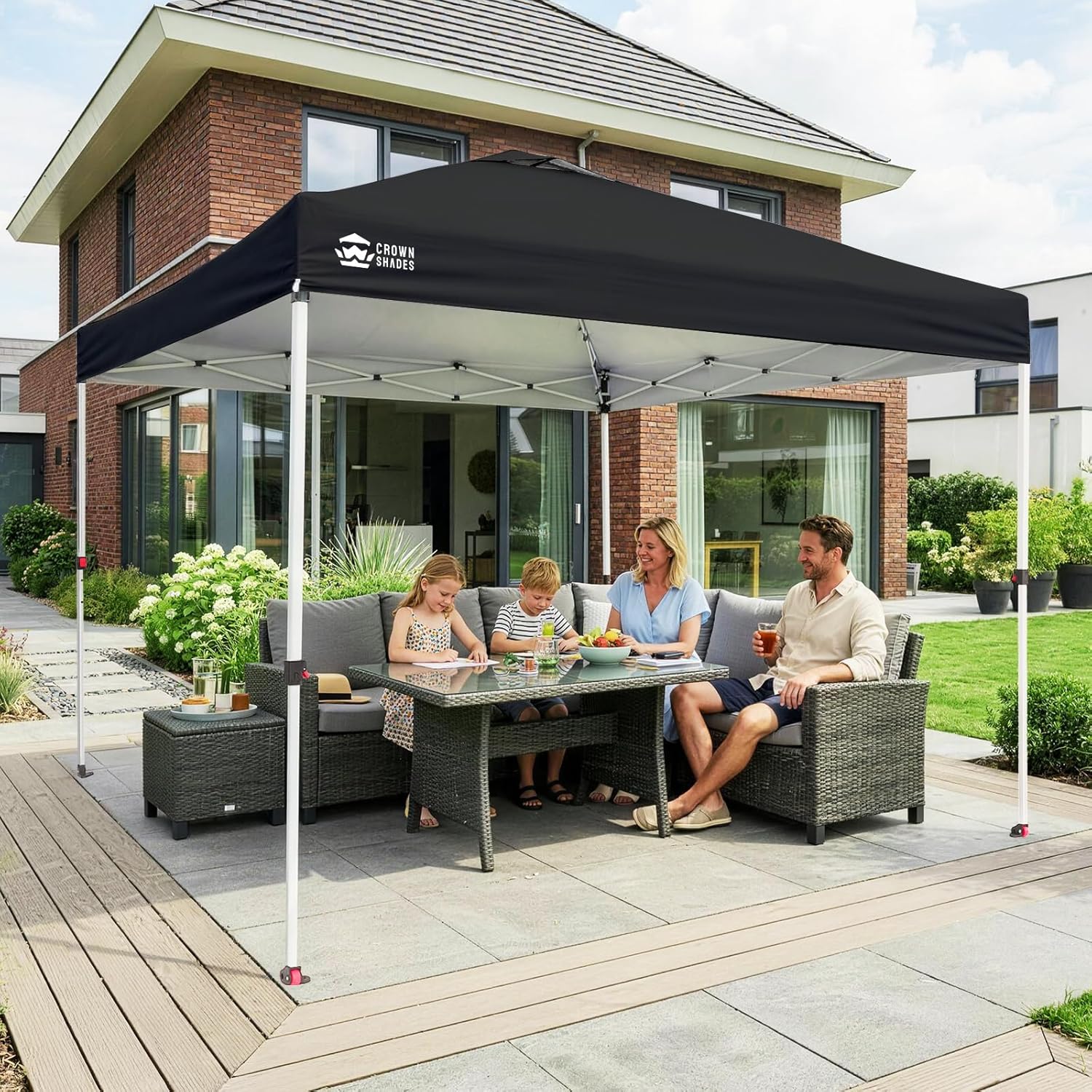 Tonnelle pliante 3x3 en place sur terrasse, famille assise autour d'une table sous l'abri noir, mobilier de jardin et maison en arrière-plan. Sono Médoc