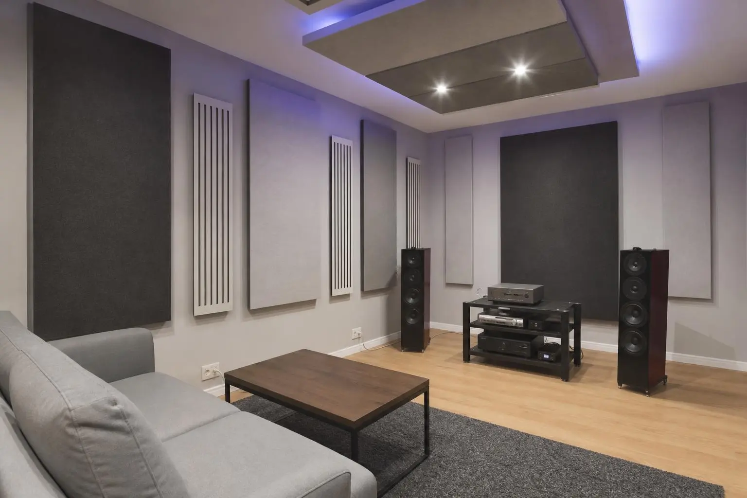 Salon équipé pour home cinéma avec enceintes haut-parleurs, meuble audio et traitements acoustiques, prêt pour comment sonoriser une salle.