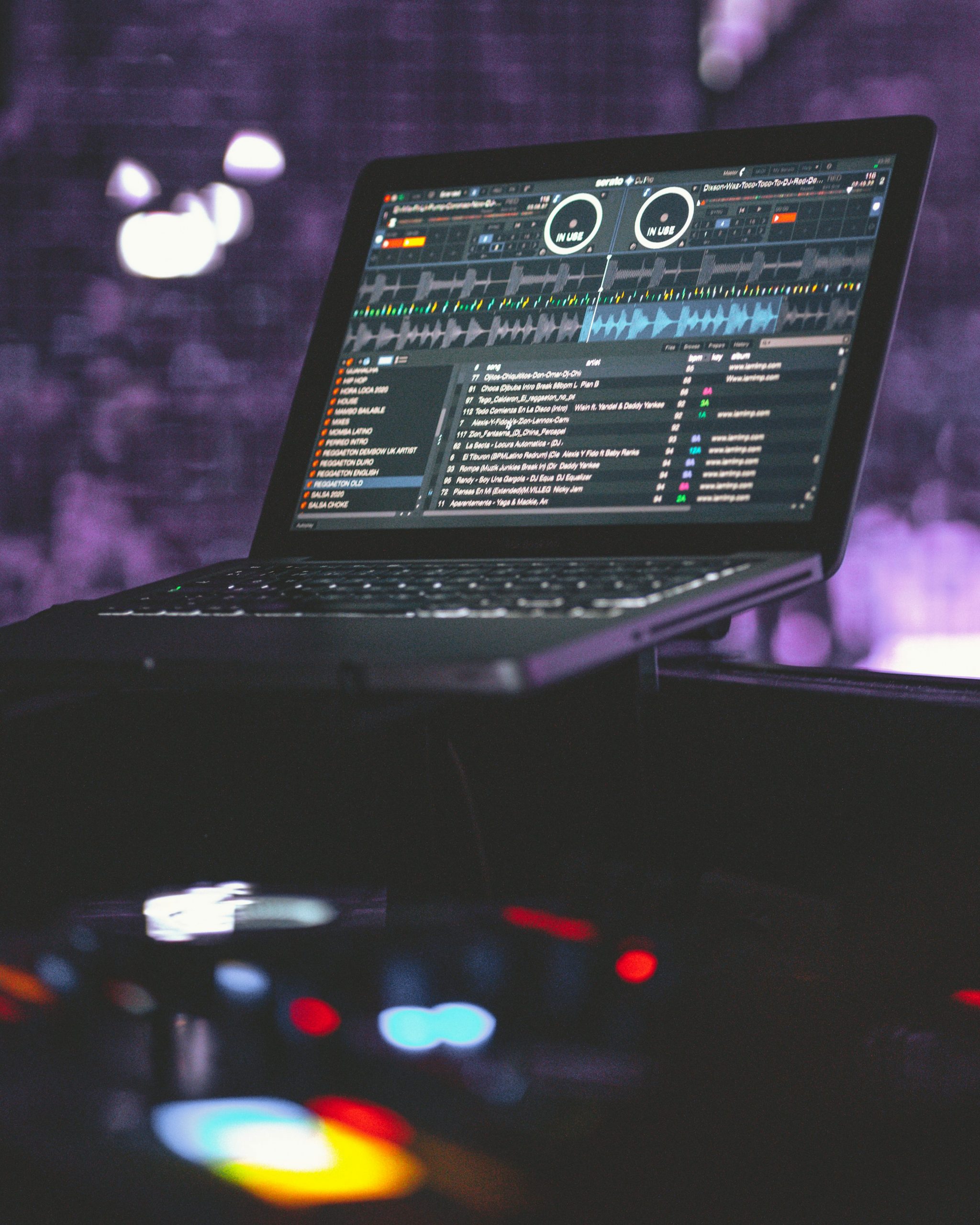 Écran d’ordinateur portable affichant une interface de logiciel DJ professional avec decks, onde sonore et liste de morceaux.
