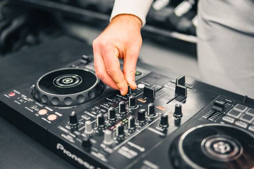 Homme ajustant les boutons d’un lecteur DJ professionnel lors d’un set, en concertation sur les platines. Comment choisir un dj pour mariage et conseils.
