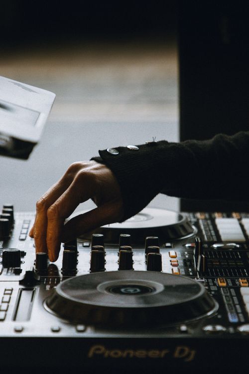 Main sujet: un DJ manipule une platine et des contrôleurs sur un appareil Pioneer DJ; ambiance studio. Meilleur logiciel dj professionnel pour accompagner les sets.