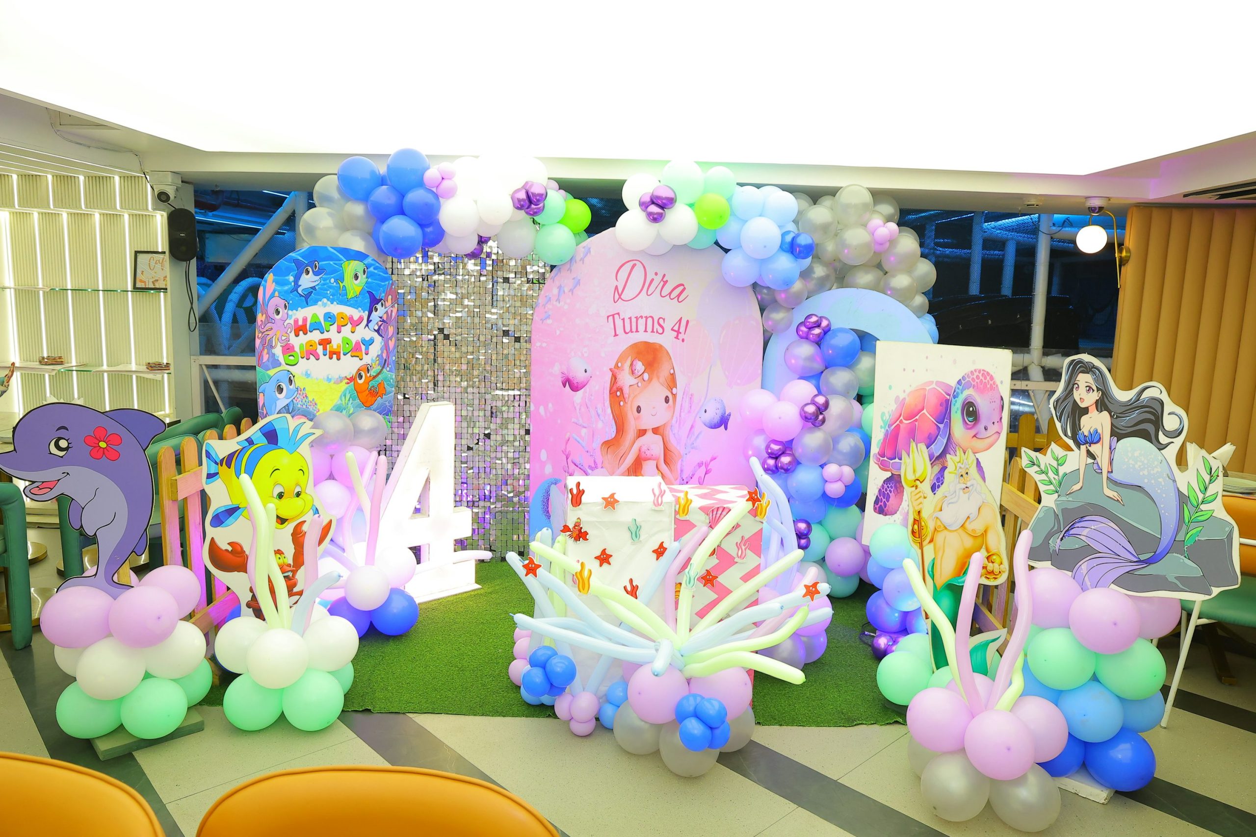 Décorations colorées et ballons en balloons pour une fête d'anniversaire, avec un thème enfantin et une grande lettre « 4 ». Matériel pour soirée d'anniversaire visible, prêt à louer.