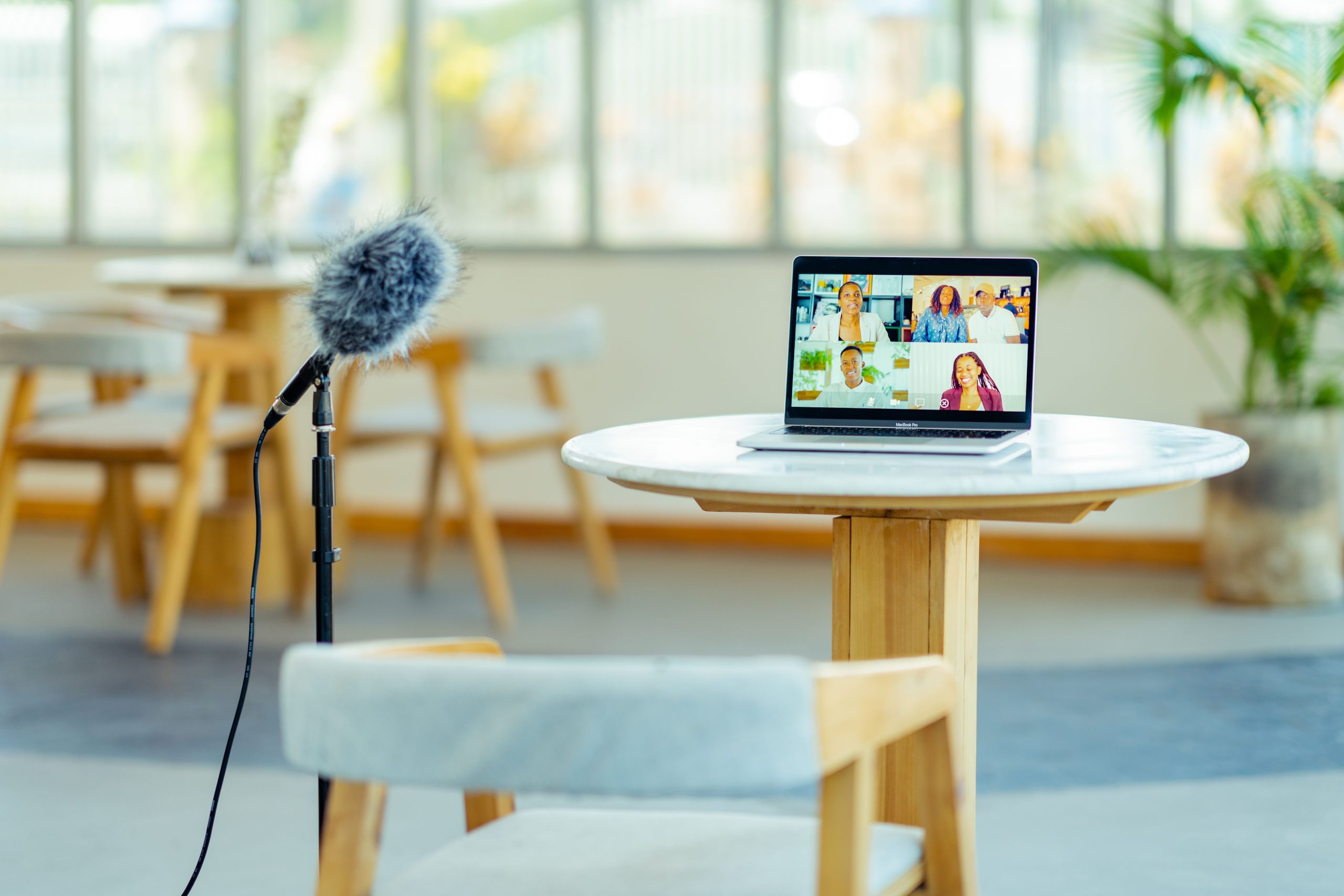 Microphone pour conférence et caméra associée à une visioconférence sur un portable posé à une table, ambiance salle de réunion lumineuse.