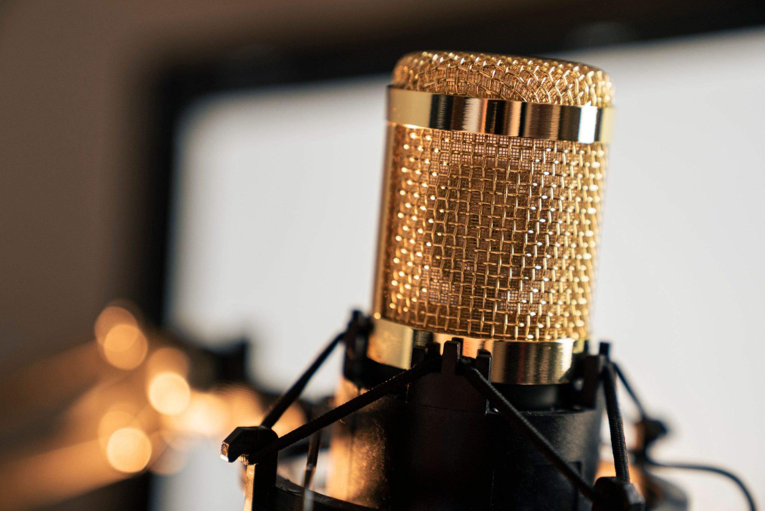 Microphone doré posé sur un support avec grillage métallique en gros plan, ambiance studio.