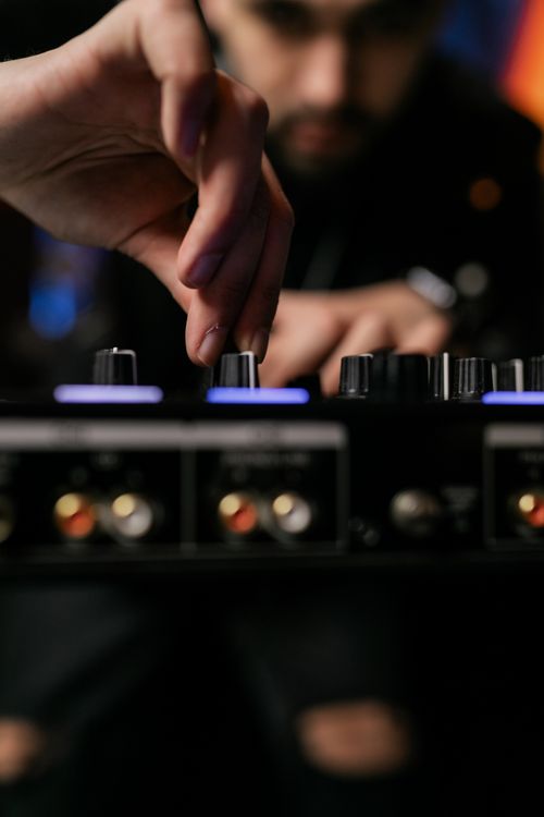 Analyste ajustant les boutons d’un console de mixage audio avec des voyants lumineux.