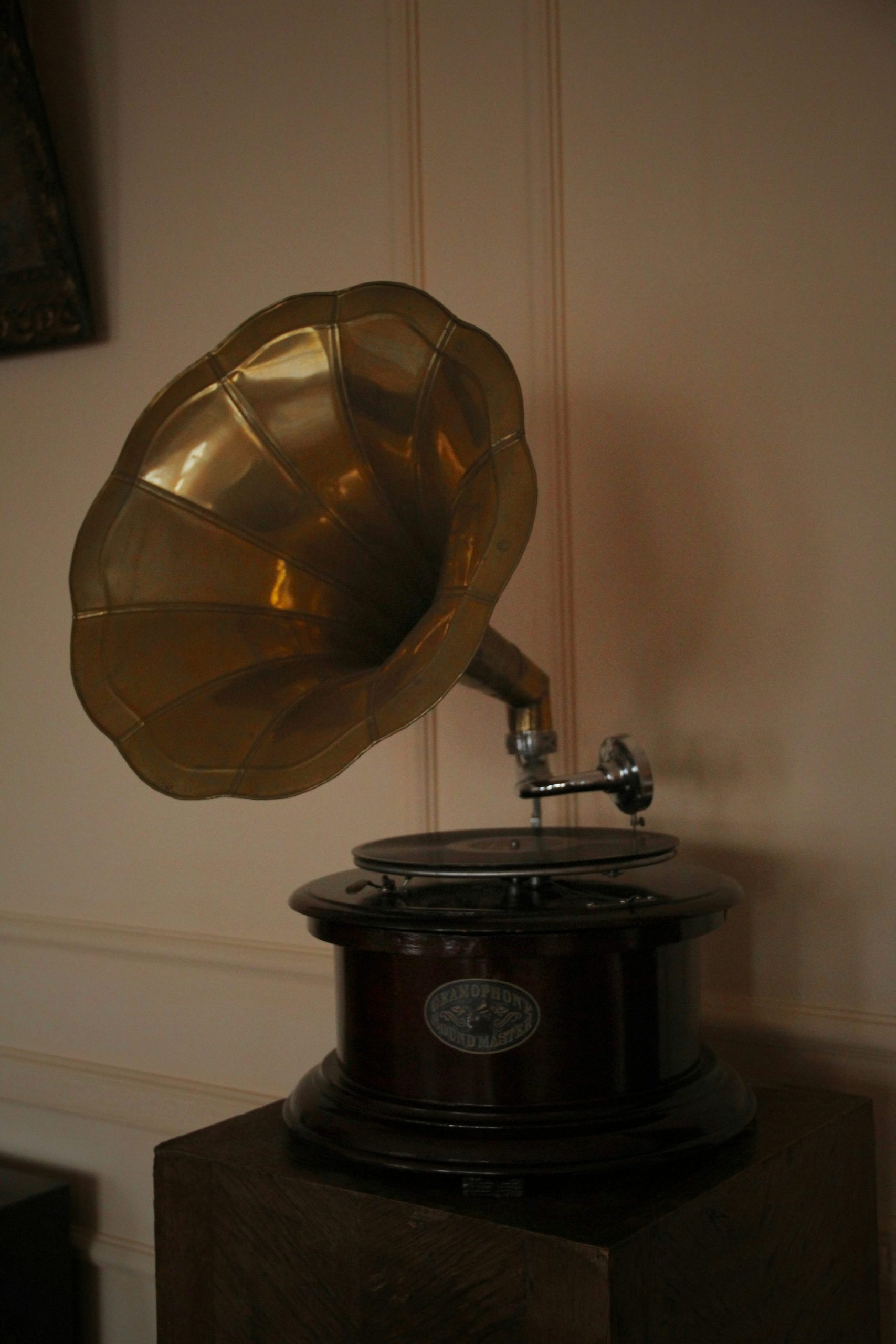 Gramophone ancien avec pavillon en bronze posé sur une étagère en bois.