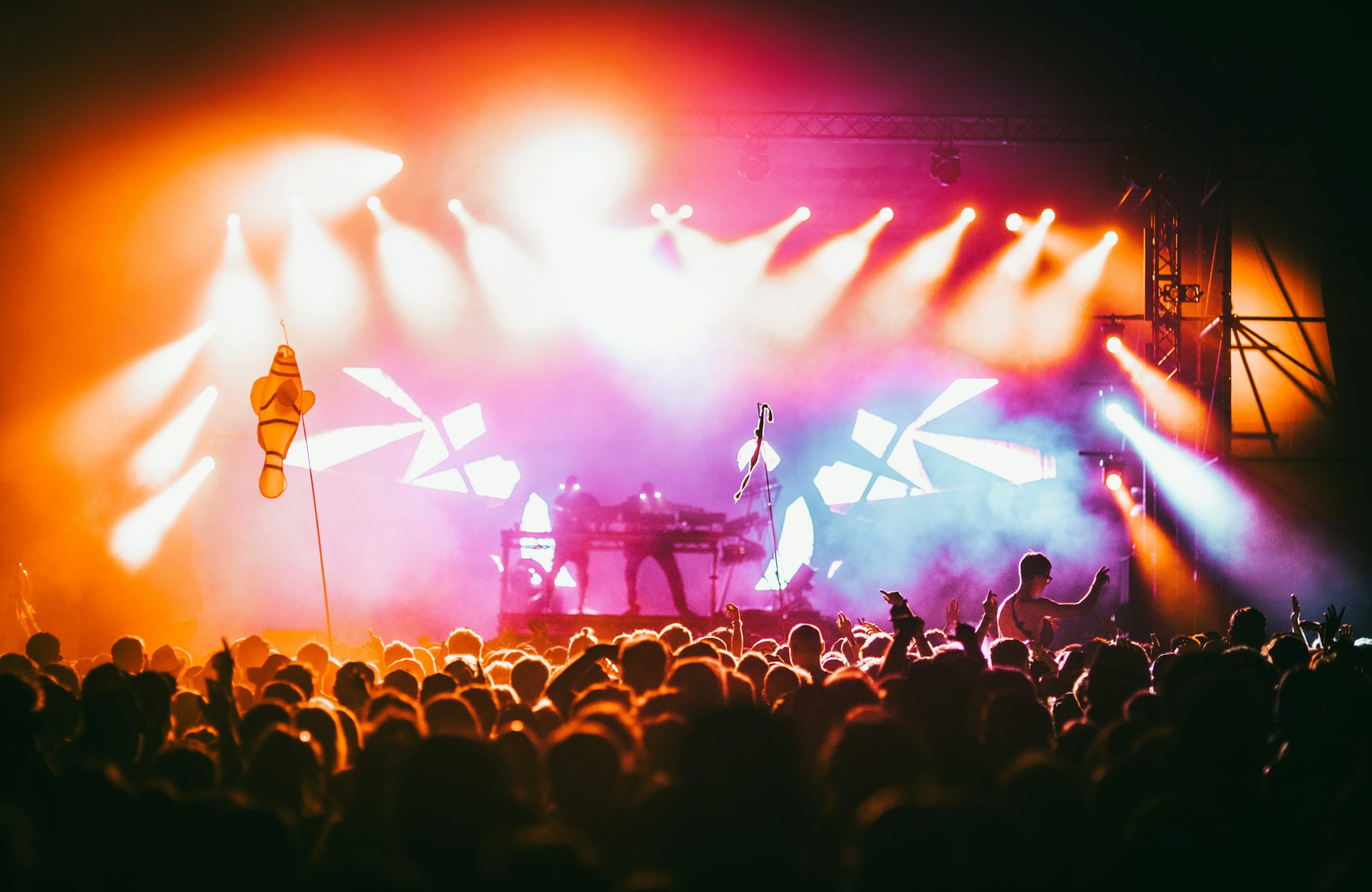 Gros plan sur une scène de concert vibrant avec éclairage multicolore et foule enthousiaste au premier plan. Gros plan sur une scène de concert vibrant avec éclairage multicolore et foule enthousiaste au premier plan.