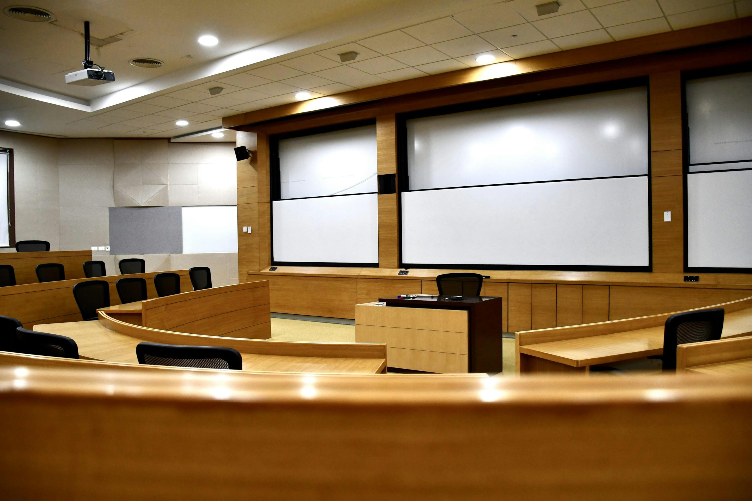 Salle de tribune ou amphithéâtre vide avec écran et pupitre au devant.